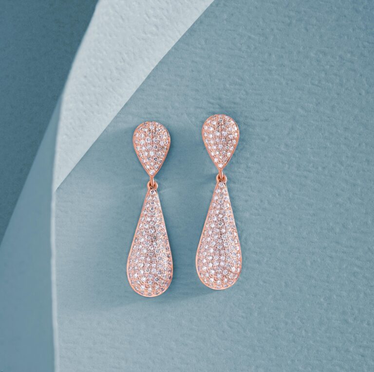 Diamond encrusted dangling earrings on a textured blue background|Best Bridal Earrings