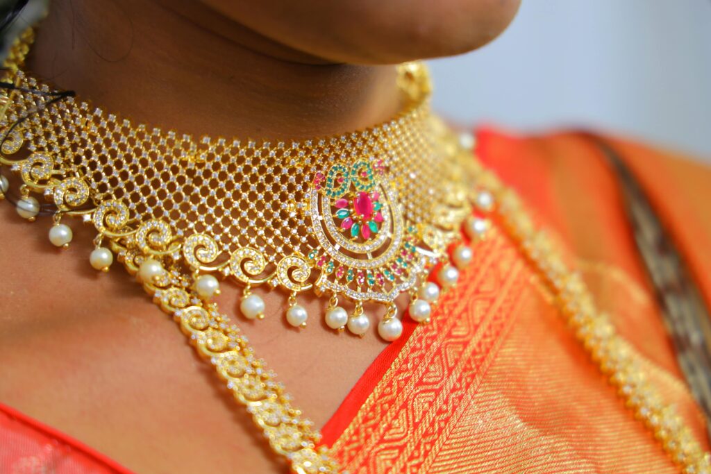 Close-up of a gold and pearl choker necklace worn with traditional attire, highlighting intricate details.